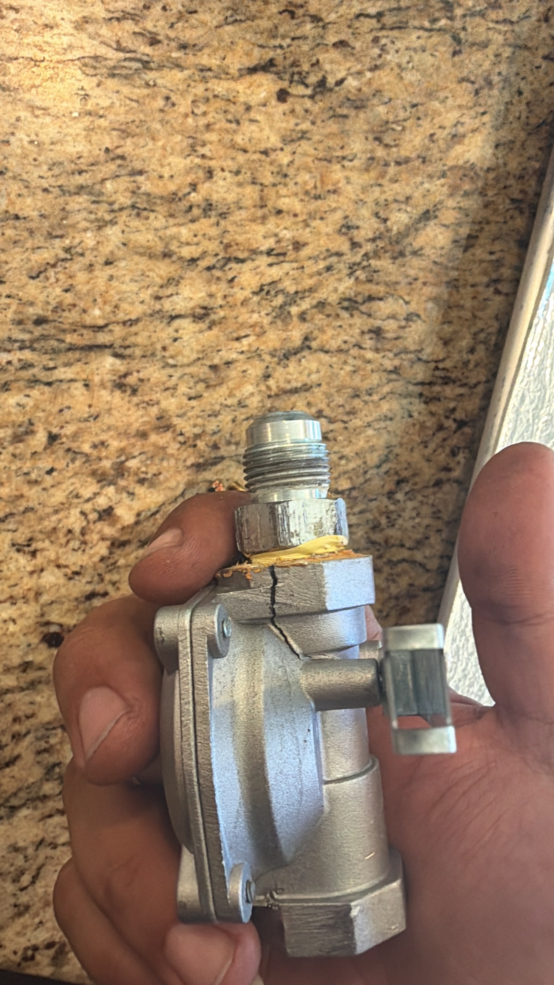 Cracked gas pressure regulator removed from the GE stove with the crack visible in the housing