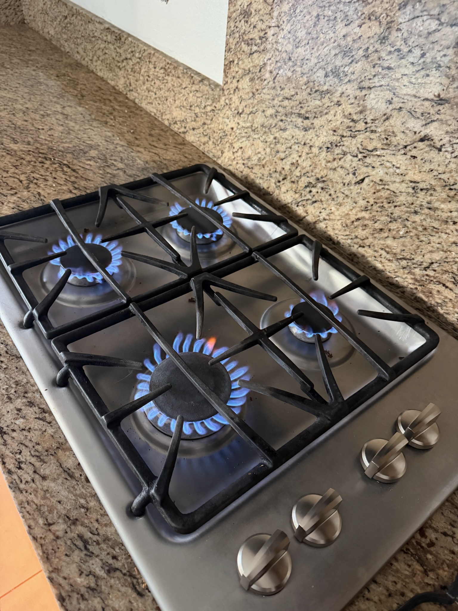 All four burners on the GE gas cooktop lit with strong, even blue flames after the repair