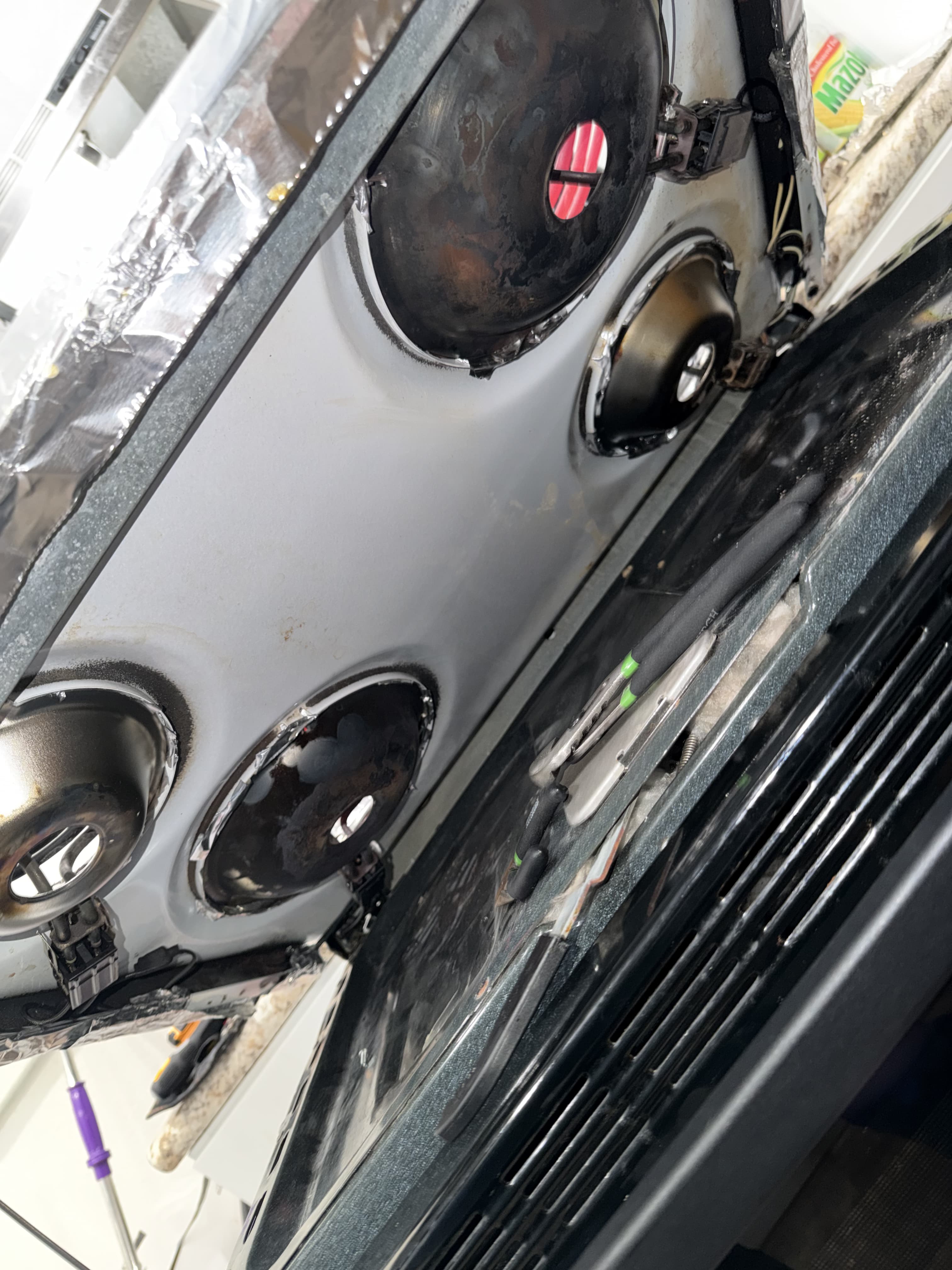 Hotpoint range cooktop lifted to access the burner connectors and wiring underneath