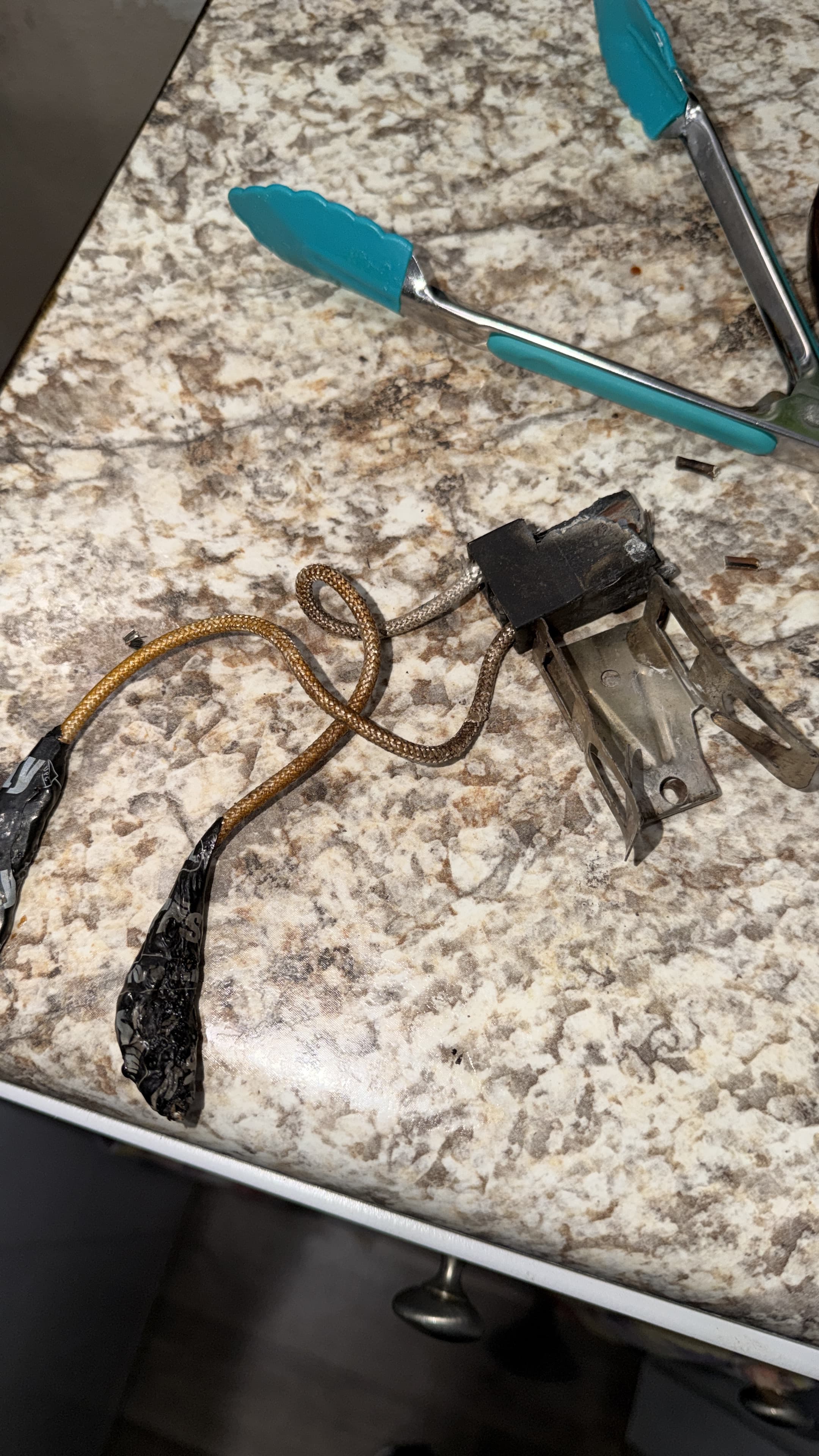Damaged burner connector and heat-scorched wiring after removal from the Hotpoint range