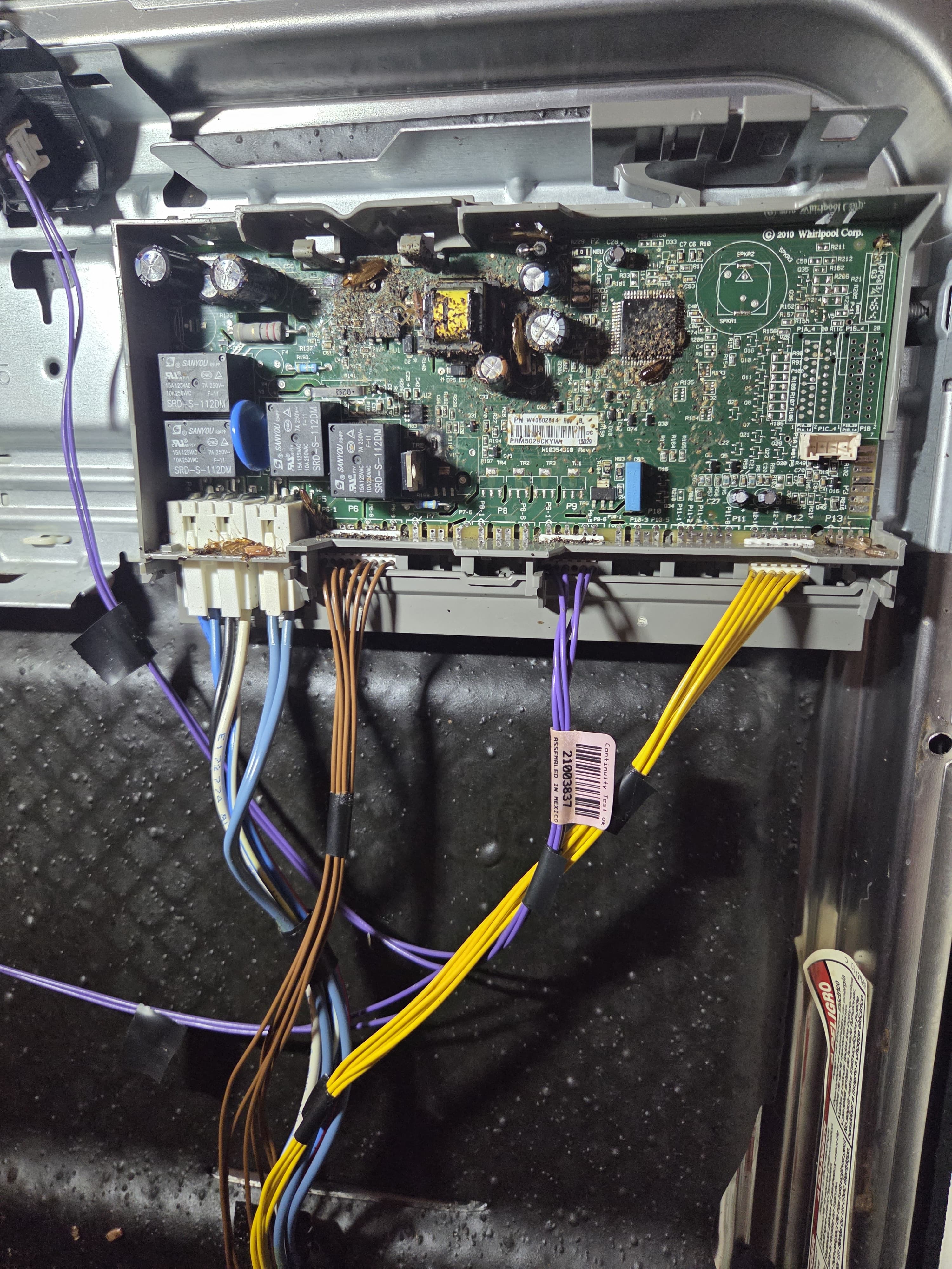 Close-up of the failed Kenmore dishwasher control board showing debris and contamination