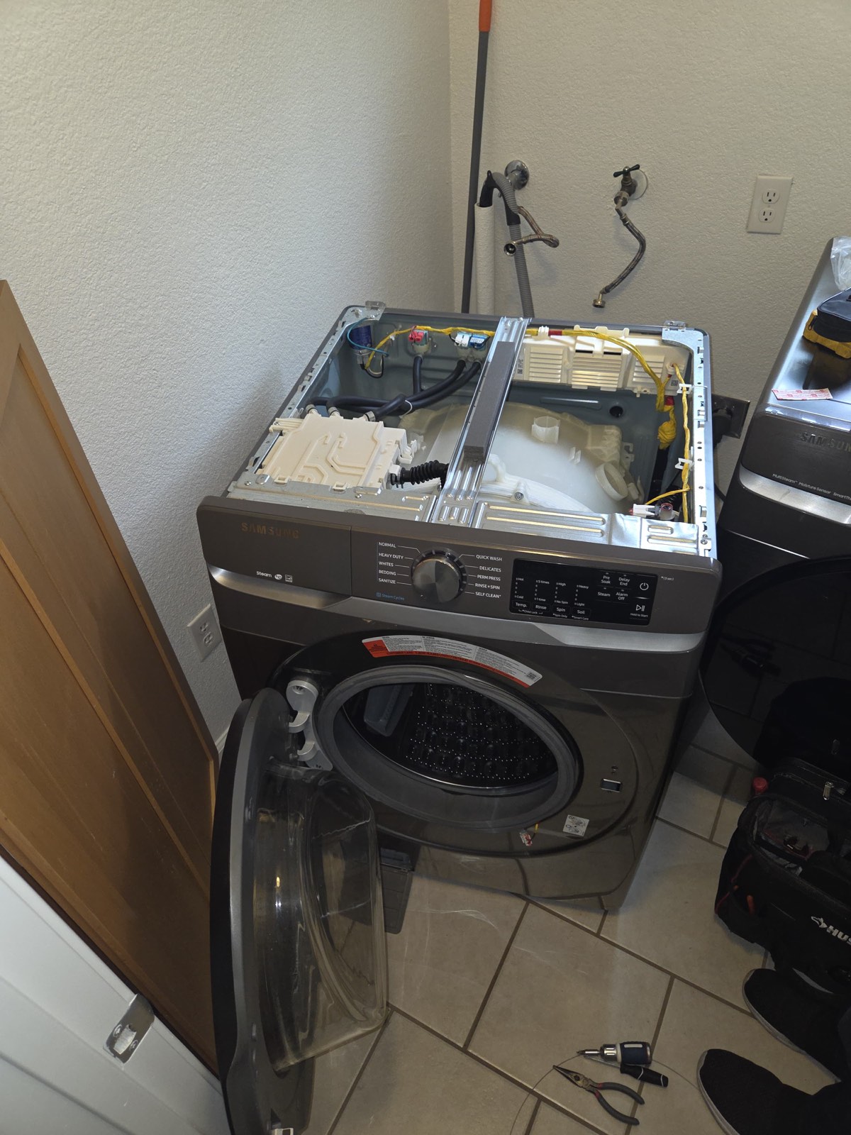 Samsung front-load washer with the top panel removed to access the door lock assembly
