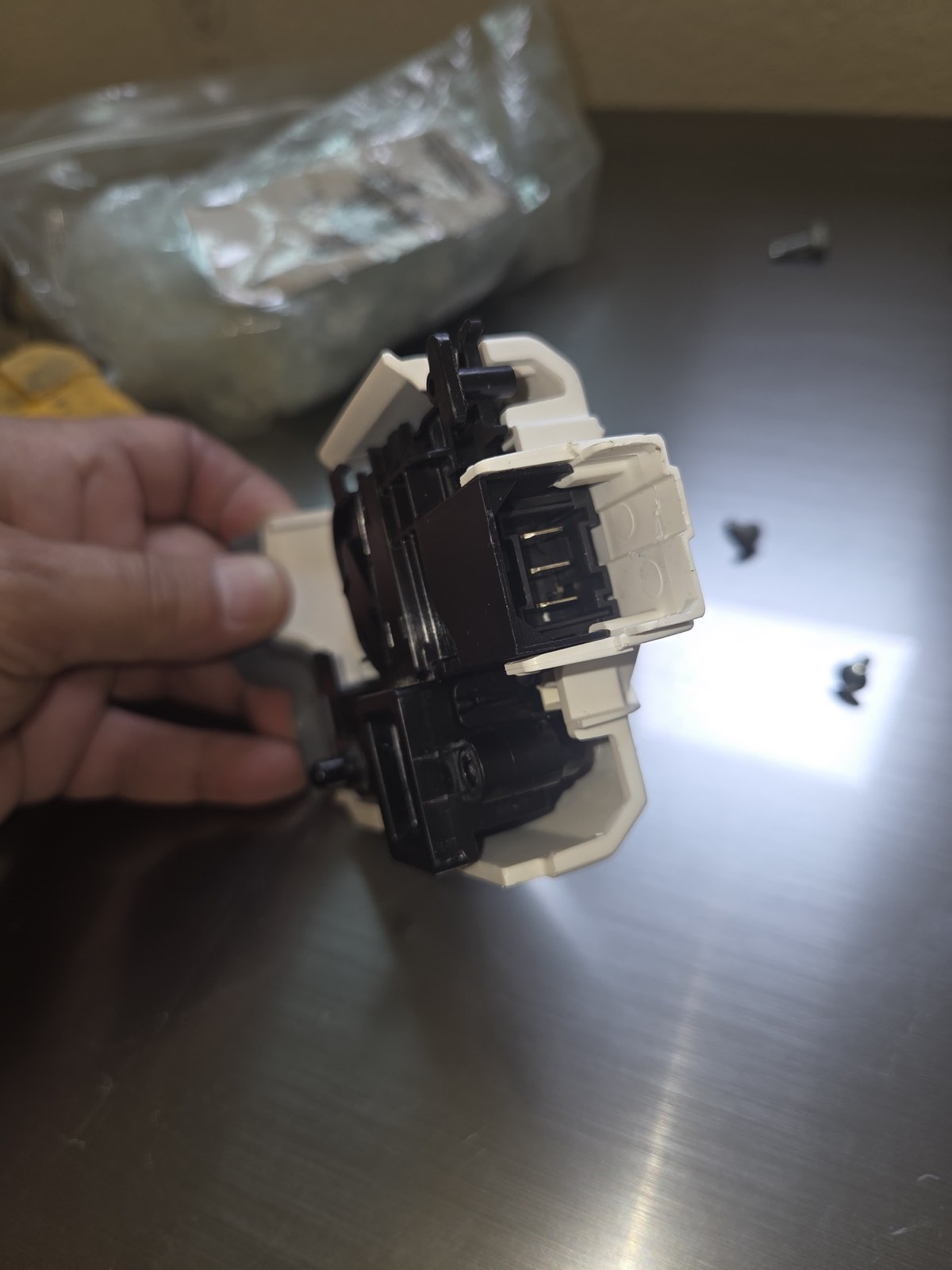 New door lock assembly held in hand before installation in the Samsung washer